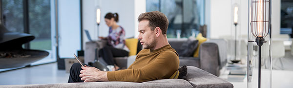 Man sat on a sofa working on a tablet