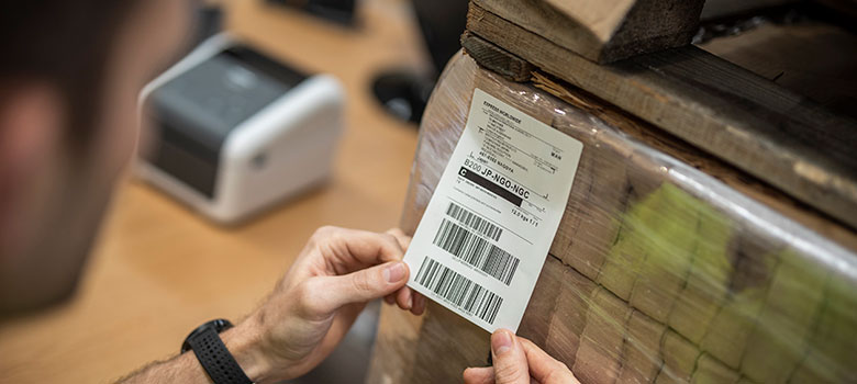 Shipping label being applied to wrapped brown boxes