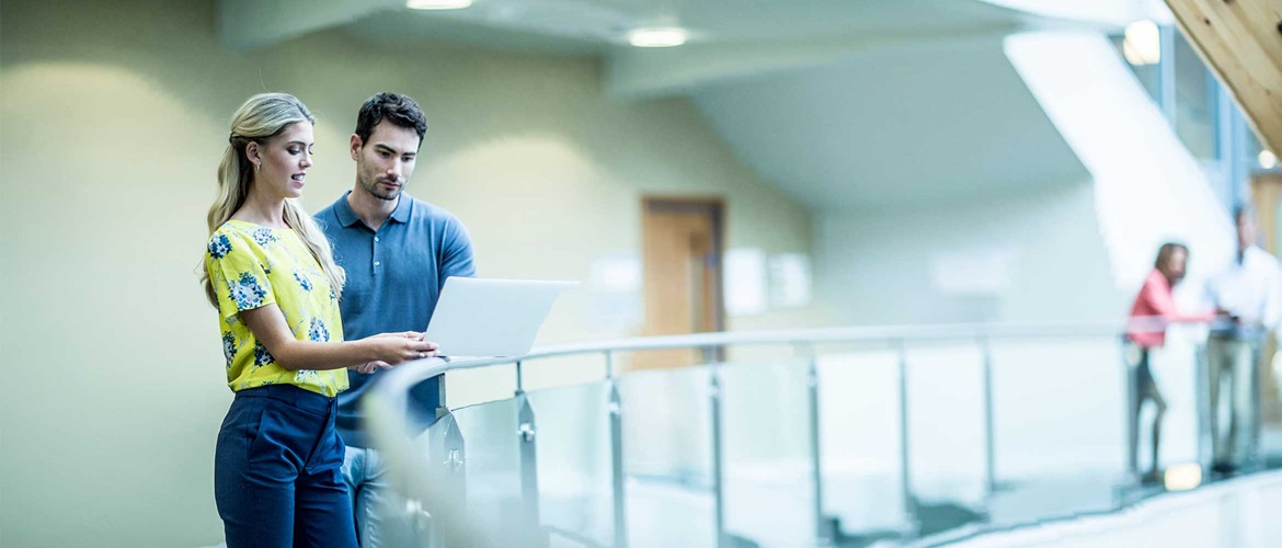 Man and woman stood in corridor looking at laptop