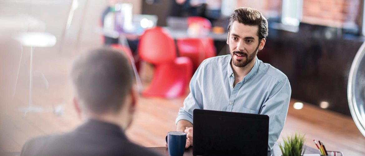 A supplier discussing a service level agreement with a customer across a desk in an office environment