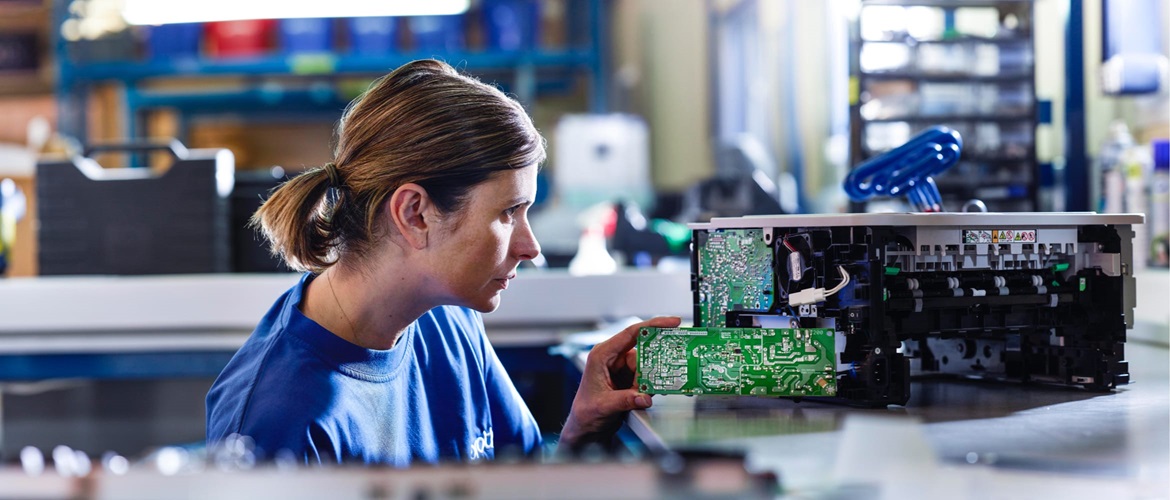 A technician dismantling an old printer in a workshop environment