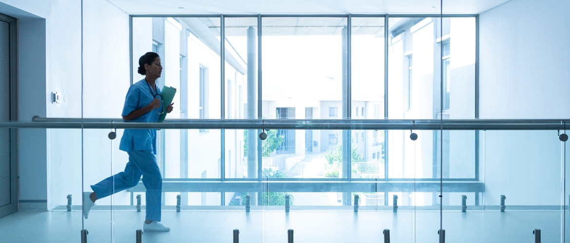 Female surgeon carrying medical reports running along a corridor in a hospital