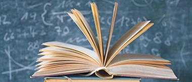 an open book in front of a blackboard