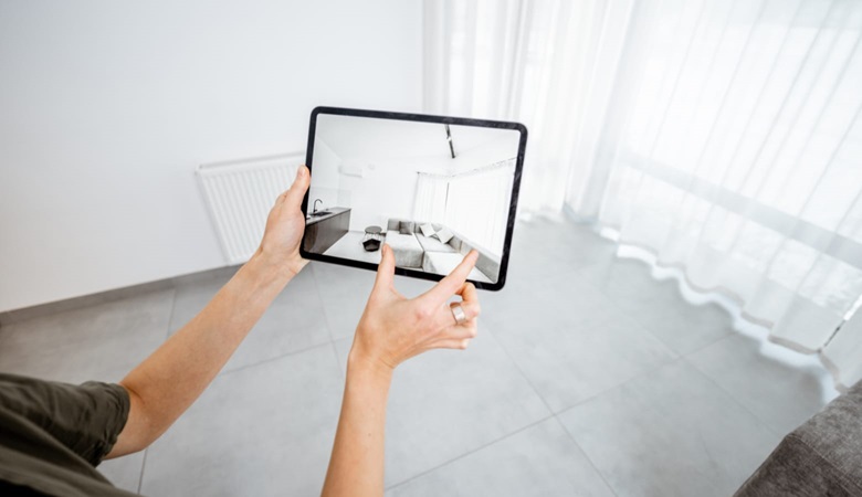 A person in an empty room using an augmented reality app on a tablet device to make interior design decisions