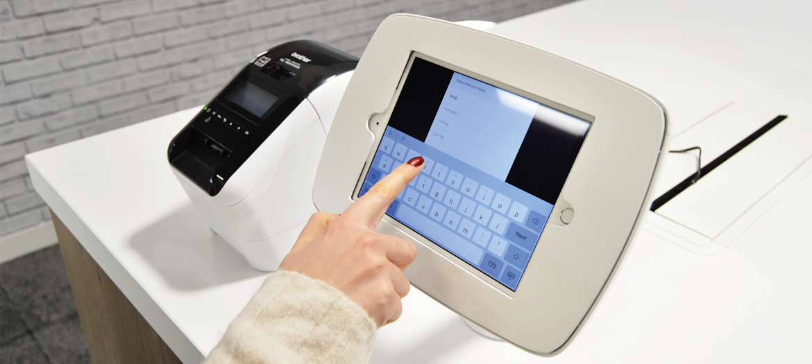 A woman entering information on a visitor sign-in touch screen