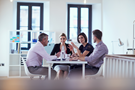 Four colleagues having a discussion around a table in an office environment